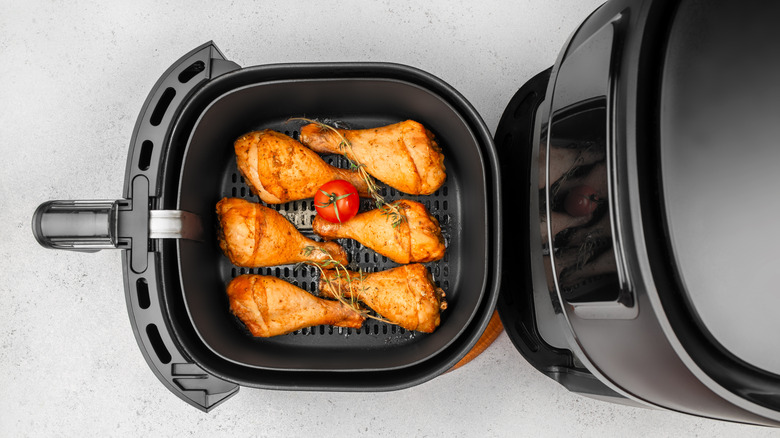 Chicken drumsticks in black air fryer on counter
