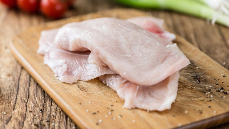 raw chicken cutlets on cutting board