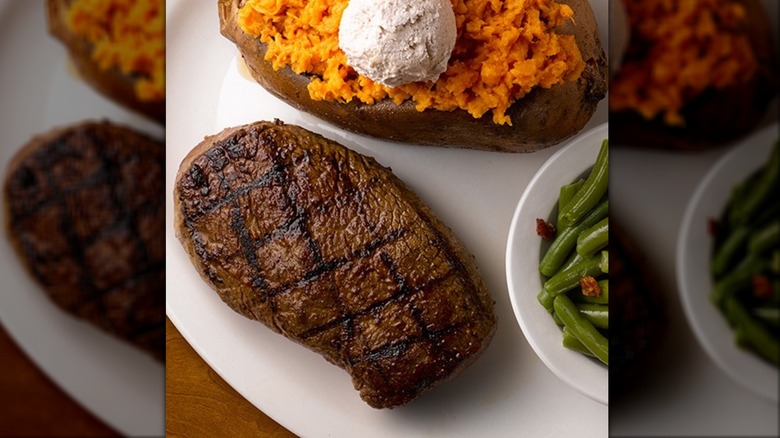 Texas Roadhouse sirloin on white plate next to side dishes