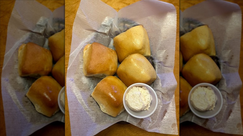 Texas Roadhouse rolls in paper-lined basket with butter