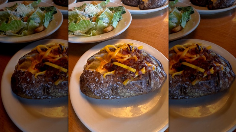 Texas Roadhouse baked potato and Caesar salad on white plates