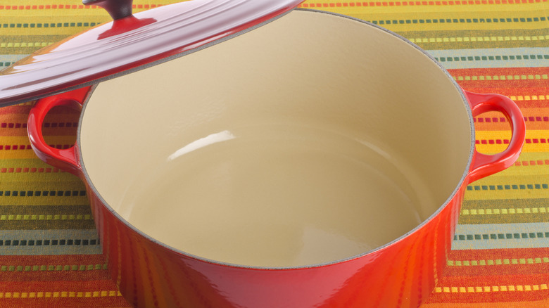 Red Dutch oven with open lid on colorful tablecloth