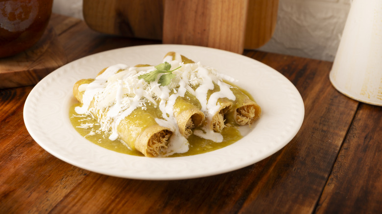 Chicken enchiladas with green sauce on white plate