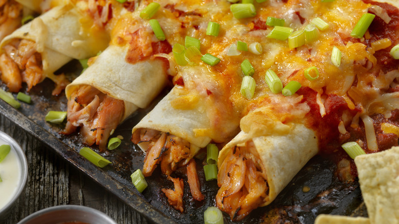 Baked chicken enchiladas with cheese and scallions on top
