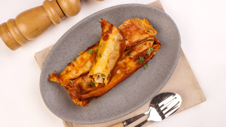 Chicken enchiladas on grey plate without a lot of sauce