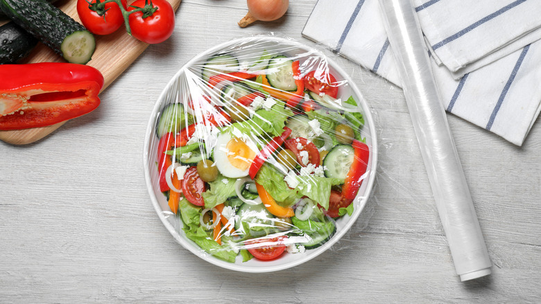 Plastic wrap stretched over bowl of salad