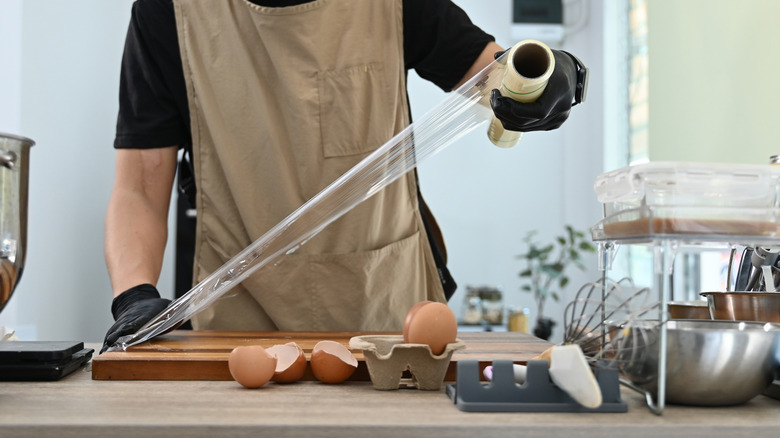 Person putting plastic wrap on cutting board