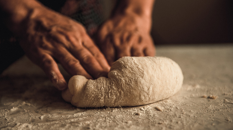 Hands kneading dough on countertop