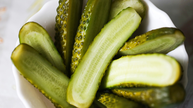 Halved half-sour pickles in a white bowl