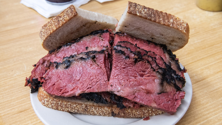 Huge pastrami sandwich on a white plate