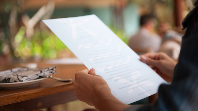 A close up of a man's hands holding a menu at a restaurant