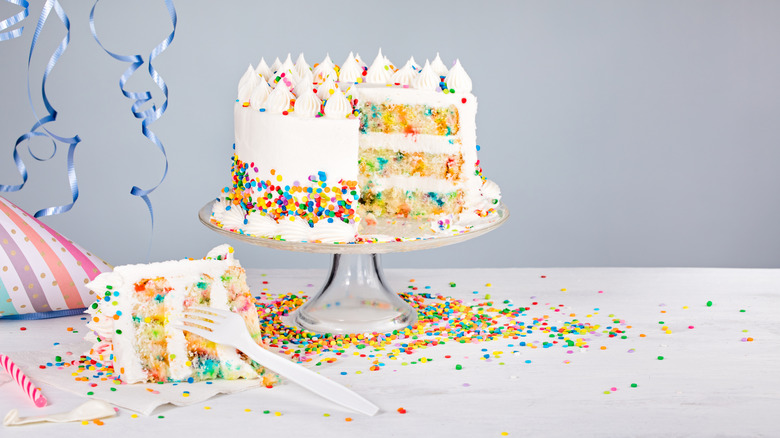 Colorful birthday cake on cake stand with sprinkles