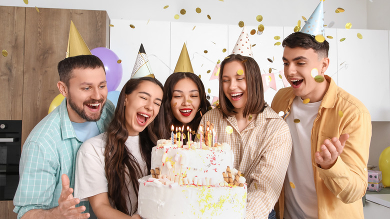 Group of people partying around a large cake