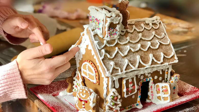 Hand decorating gingerbread house
