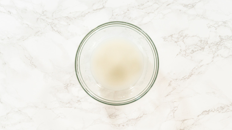 Glass bowl of white royal icing on countertop