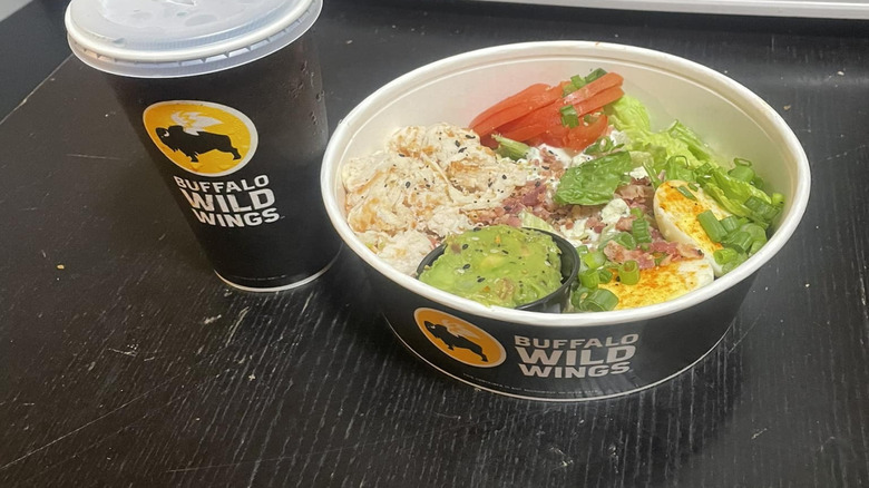 Salad and drink from Buffalo Wild Wings on black table
