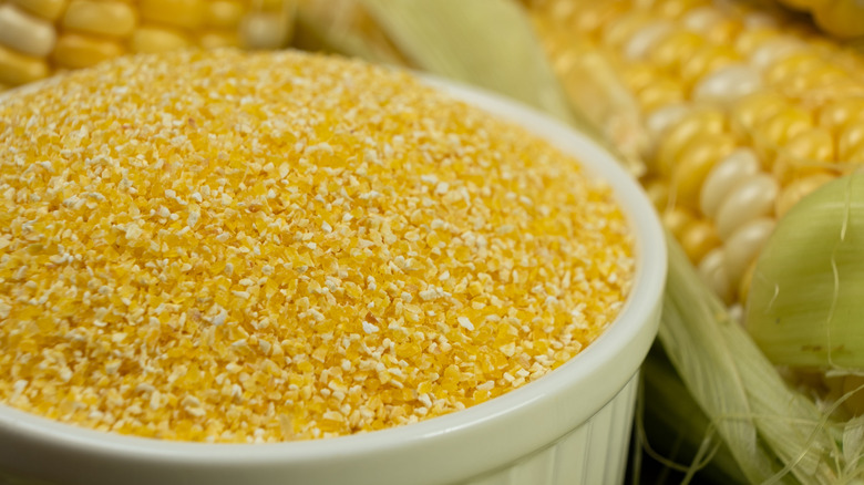 White bowl of dry, uncooked grits with corn in background