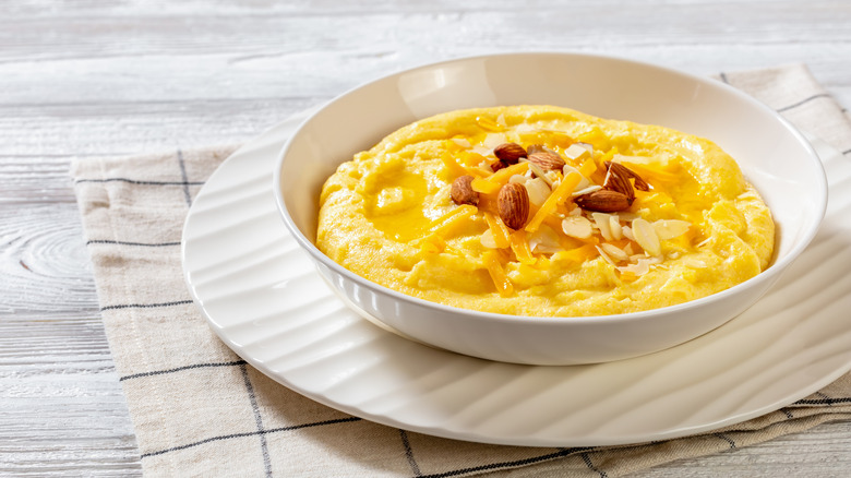 White bowl of grits topped with nuts and cheese