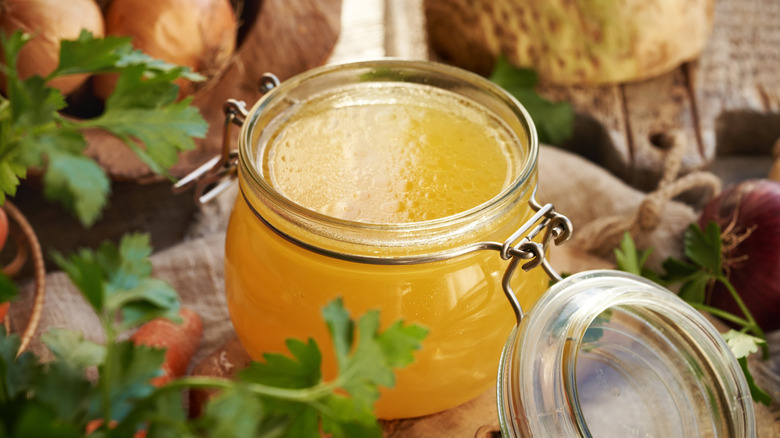 Chicken broth in a glass jar with parsley in foreground