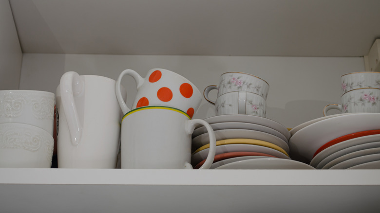 White wood cupboard with porcelain cups and plates
