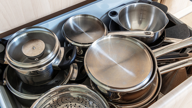 Pans and their lids in an opened kitchen storage drawer