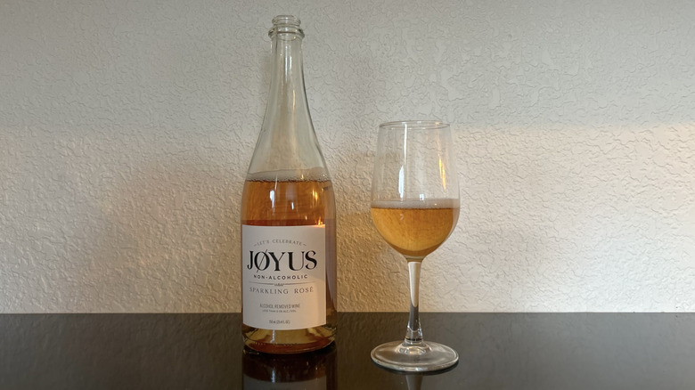 A bottle and glass of Jøyus Non-Alcoholic Sparkling Rosé