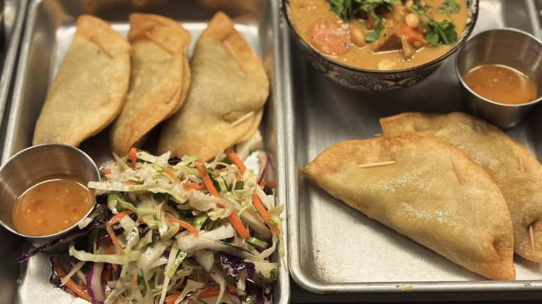 Metal trays of fried tacos and side dishes