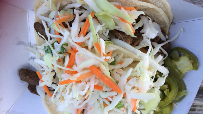 Slaw on beef tacos on a white container