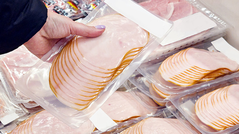 hand picking up packaged ham in grocery store