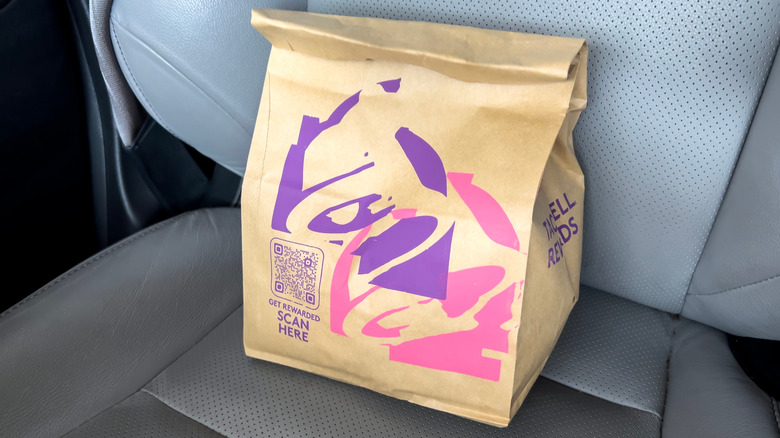 Close up view of a Taco Bell fast food bag inside of a car
