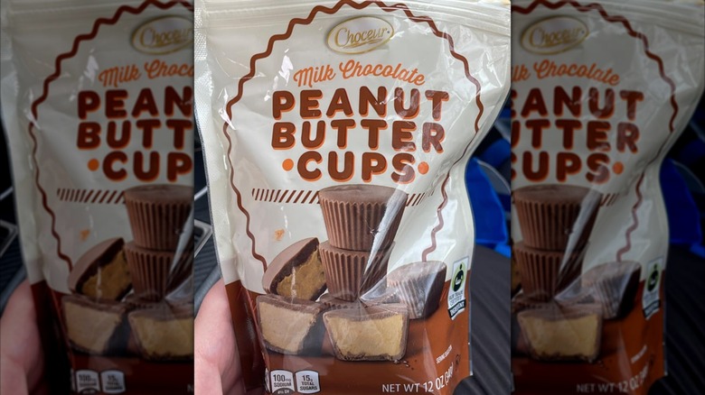 Hand holding Choceur Peanut butter cups in car, mirrored image