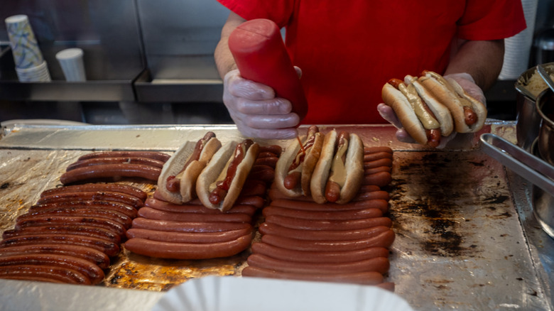 man cooking hot dogs at hot dog stand