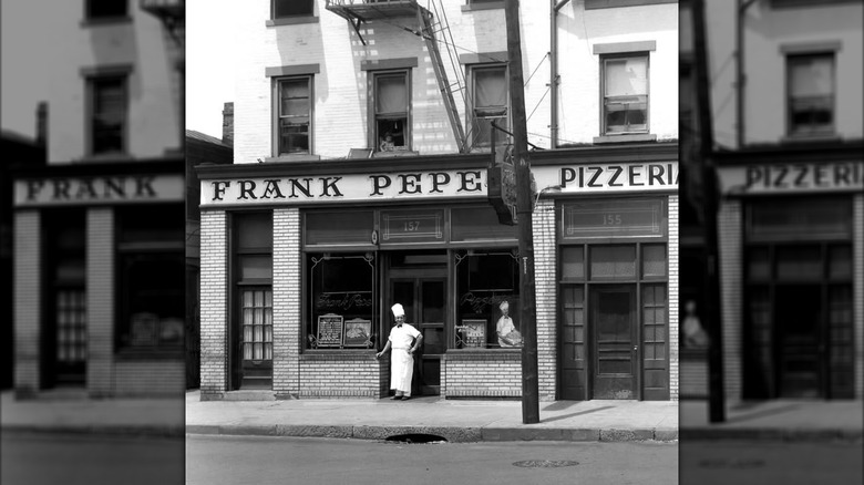 Black and white image of Frank Pepe Pizzeria Napoletana storefront with chef standing outside