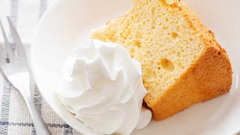 Slice of chiffon cake on white plate with whipped cream