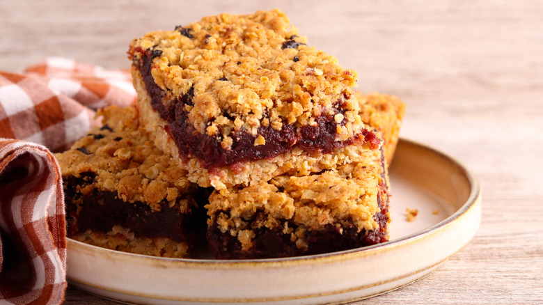 Oat bars with date and apple filling on a plate next to red and white table cloth