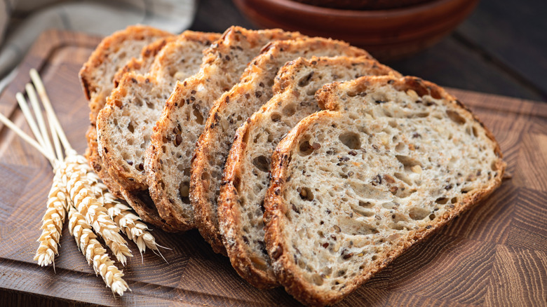Whole wheat and sourdough bread sliced on a wooden cutting board