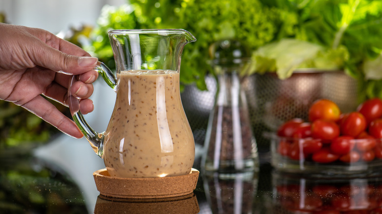 hand holding a carafe of celery seed dressing
