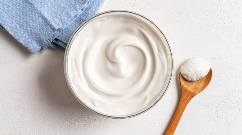 bowl of sour cream with wooden spoon of sour cream