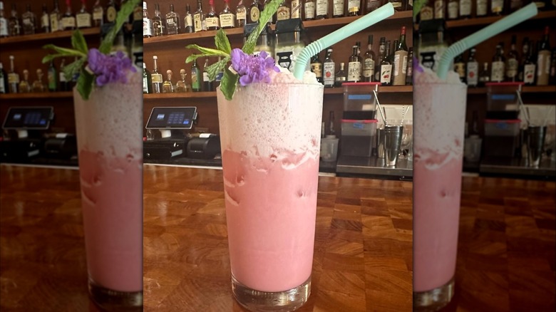 Mirrored image of cherry phosphate with straw and flower decoration on a bar