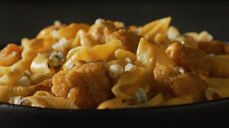 a close up of devour buffalo chicken mac and cheese in a black bowl