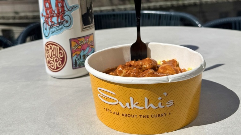 Sukhi's chicken and rice meal on a white table next to a water bottle