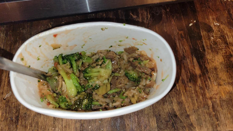 a consumer photo of a tai pei beef and broccoli frozen meal microwaved and placed on a wood countertop