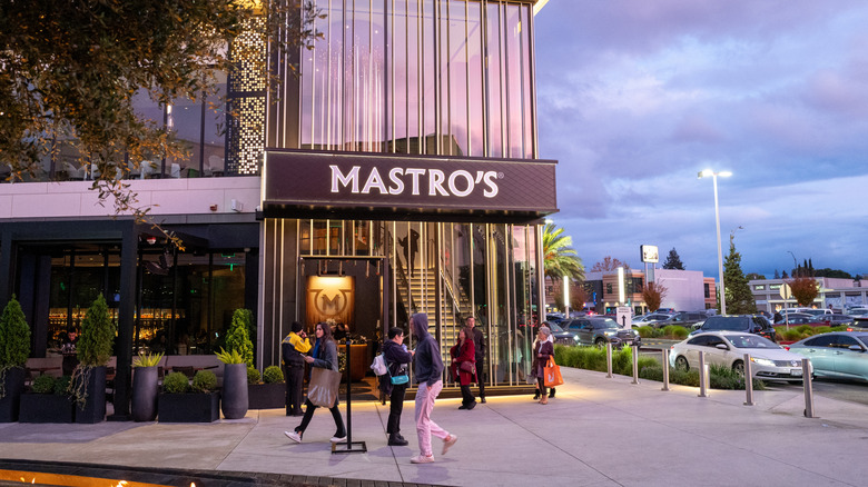 Exterior view of the front of Mastro's Steakhouse as people walk by