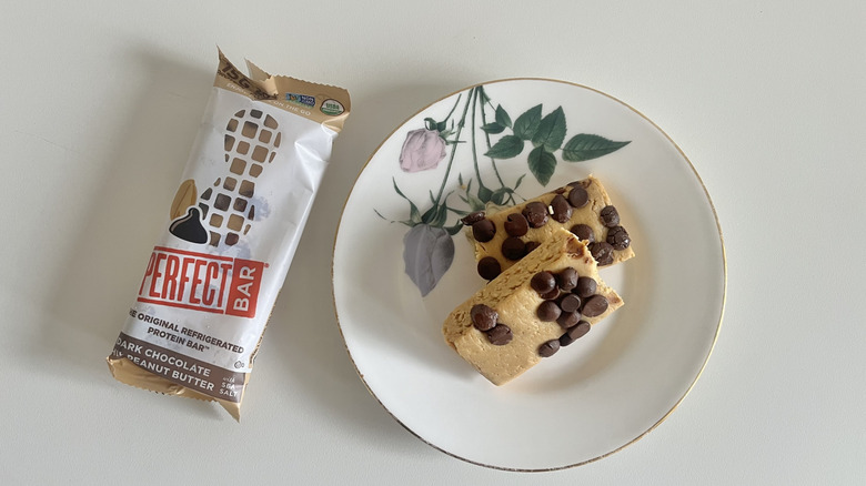 Dark Chocolate Peanut Butter Perfect Bar on a plate next to the wrapper