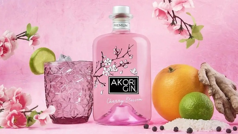 A styled shot of Akori Cherry Blossom Gin next to a filled glass and surrounded by ingredients