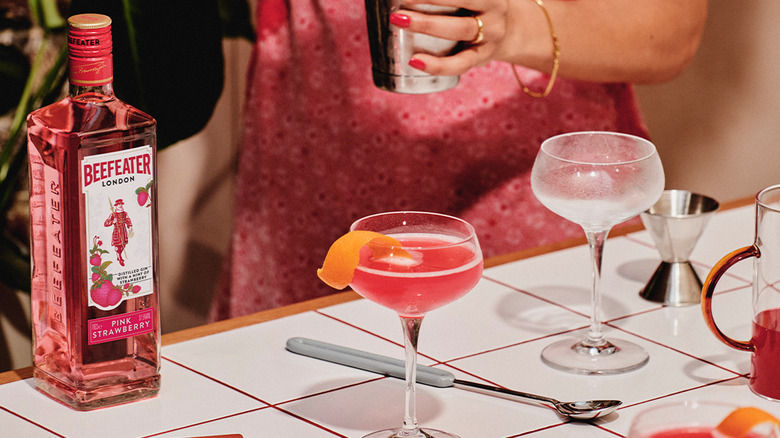 Beefeater Gin London Pink on a table next to cocktail glasses and accessories