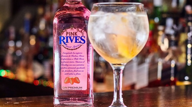A bottle of Rives Pink Gin placed on a bar next to a filled glass