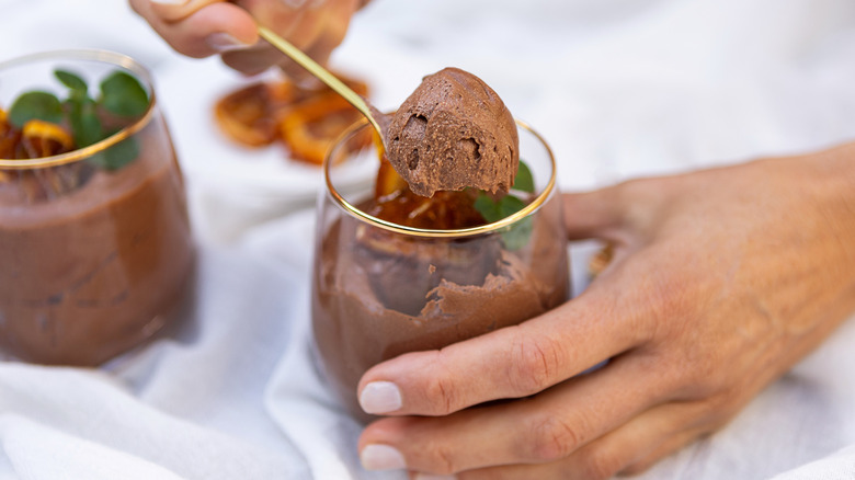 Hand spooning chocolate mousse from dessert glass