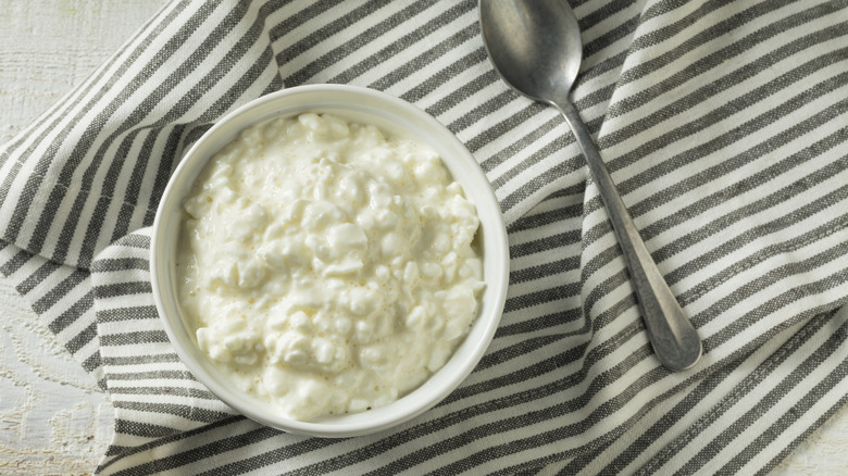 Cottage cheese in white bowl on top of grey striped linen