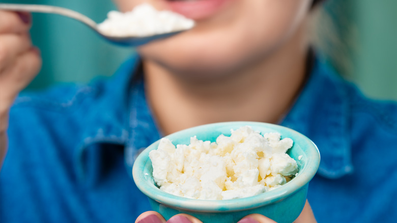 Person spooning cottage cheese from blue bowl